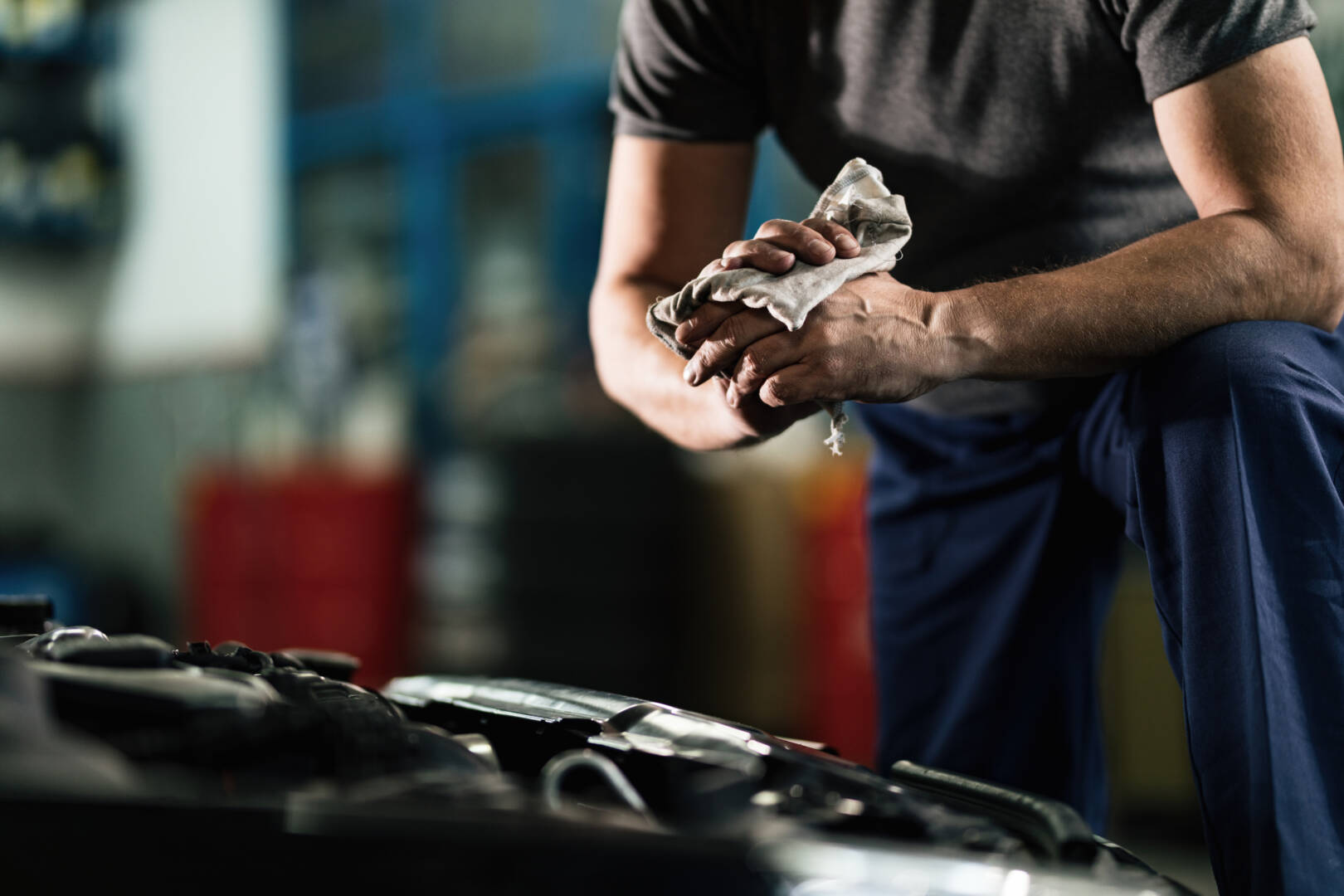 Unrecognizable auto mechanic wiping his hands in a repair shop.